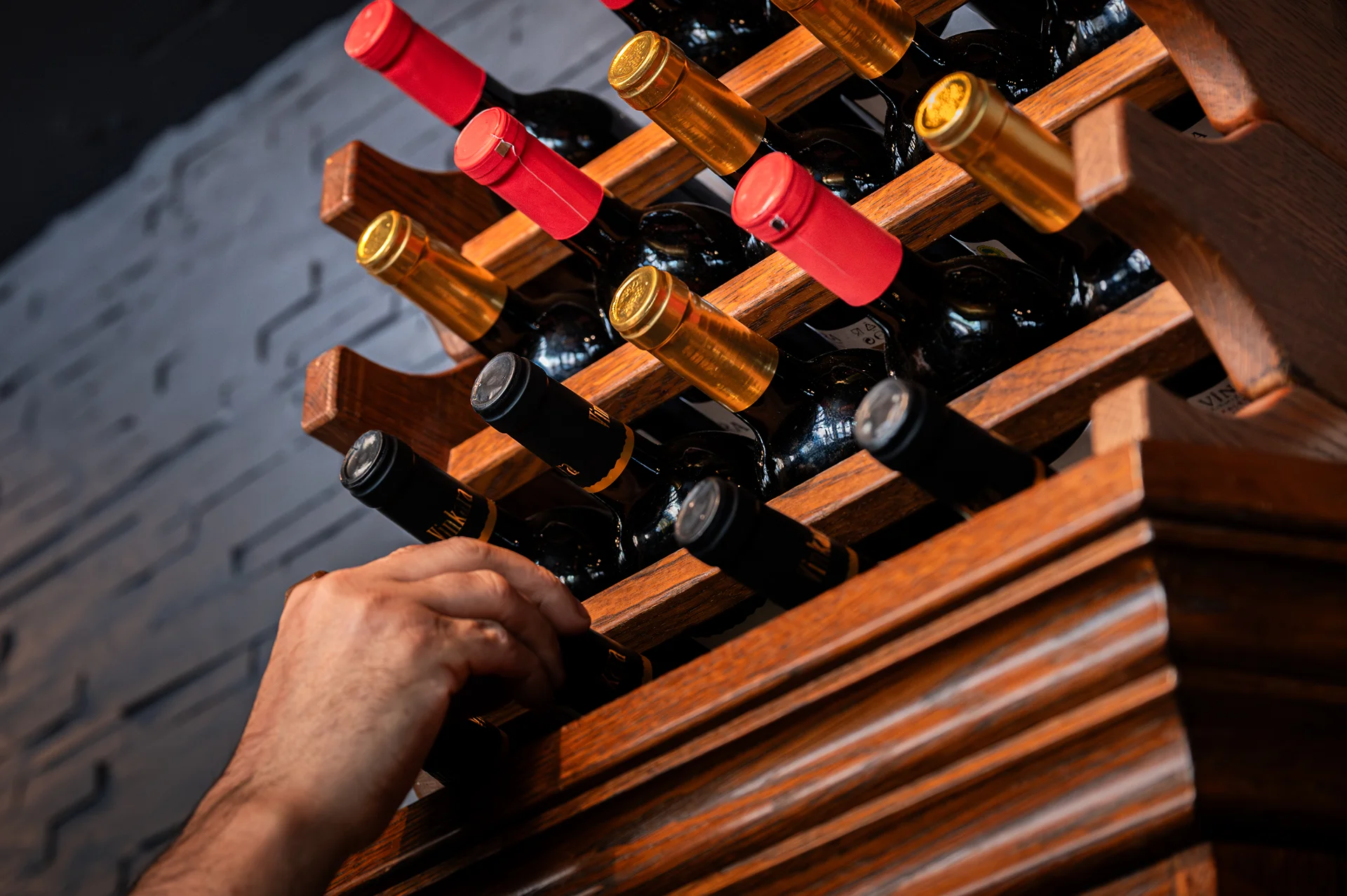 Hand selecting wine bottles from a rack